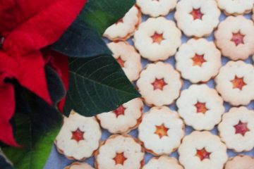 An image of Almond biscuits on a baking tray with a plant next to it.