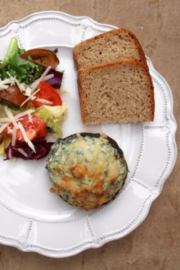 An image of Mushrooms Stuffed with Ricotta and Spinach, a salad with tomatoes and slices of bread on a white plate.