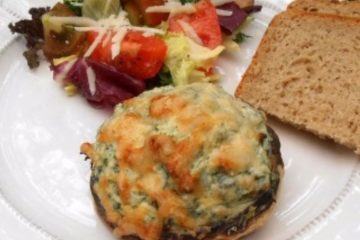 An image of Mushrooms Stuffed with Ricotta and Spinach, a salad with tomatoes and slices of bread on a white plate.