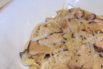 An image of Spaghetti Squash with Mushroom Sauce in a white bowl, on a white towel, on a wooden floor.