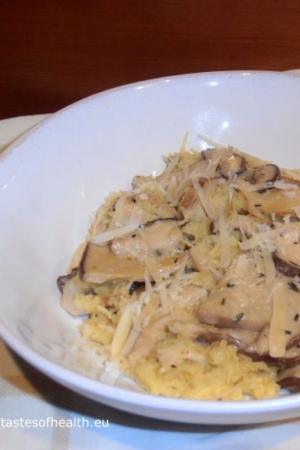 An image of Spaghetti Squash with Mushroom Sauce in a white bowl, on a white towel, on a wooden floor.