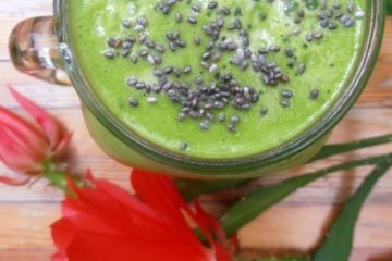An image of a Spinach and Pineapple Smoothie with chia seeds on top with a red bloom next to it.