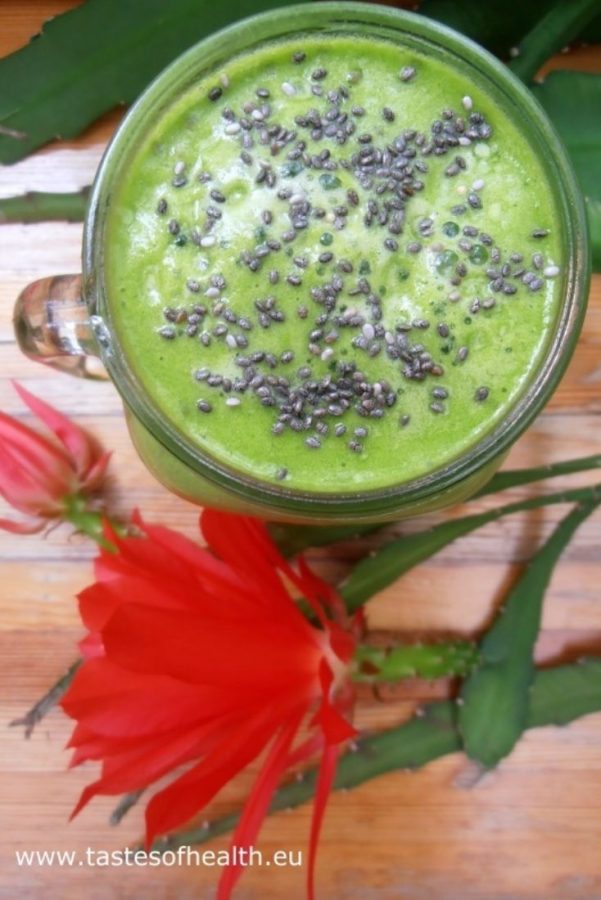 An image of a Spinach and Pineapple Smoothie with chia seeds on top with a red bloom next to it.