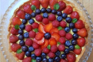 Fruit Tart with creme Patissiere seen from above: a round tart decorated with strawberries, blueberries, raspberries and mint leaves.