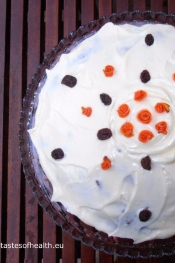 An image of a Healthier carrot Cake with white icing and orange and brown decoration on top.