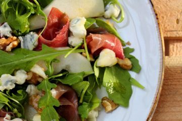 Pear and Gorgonzola Salad with Pecans, rocket and prosciutto on a white plate