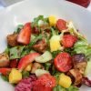 Miso Marinated Tofu Salad consists of pieces of fried marinated tofu, mango, cucumber, cherry tomatoes, strawberries and colorful lettuce leaves.