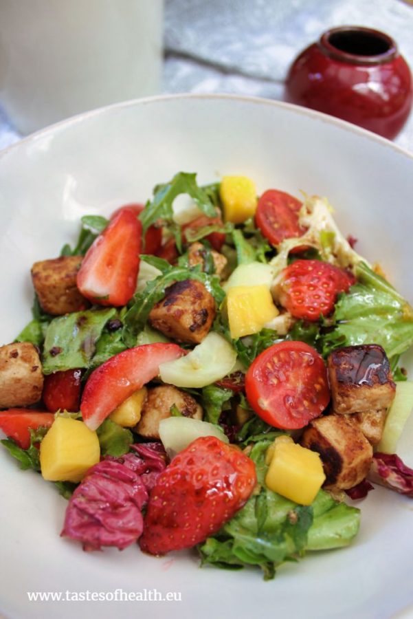 Miso Marinated Tofu Salad consists of pieces of fried marinated tofu, mango, cucumber, cherry tomatoes, strawberries and colorful lettuce leaves.